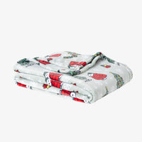A green holiday Peanuts Printed VelvetLoft Throw folded neatly on a white surface.