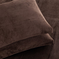 A close-up of two brown corduroy pillows stacked on a matching brown corduroy surface, showing the ribbed fabric texture in warm brown tones.