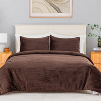 A bed dressed in a brown corduroy comforter and two matching brown pillowcases, styled in a bedroom with a white headboard, nightstands, a lamp, and wall art.