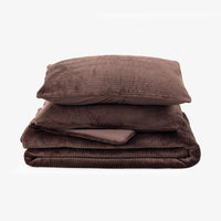 A folded bedding set in a dark brown corduroy fabric, including a folded blanket and a matching pillowcase, stacked on a plain white background.
