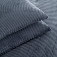 A close-up of two folded corduroy pillows in a slate blue-gray color, showcasing the ribbed texture of the fabric.