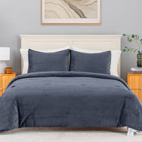 A navy blue corduroy comforter set with matching pillow shams on a bed, styled in a modern bedroom with a cream headboard, wooden nightstands, and a gray wall.