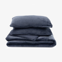 A folded navy blue corduroy comforter with a matching pillowcase stacked on top of a matching corduroy comforter, shown against a plain white background.