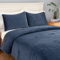 A navy blue corduroy bedding set, including a comforter  and two matching pillowcases, styled on a bed with white pillows and a light wood headboard in a bedroom setting.