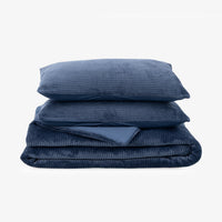 Navy blue corduroy comforter set folded neatly on a white surface.