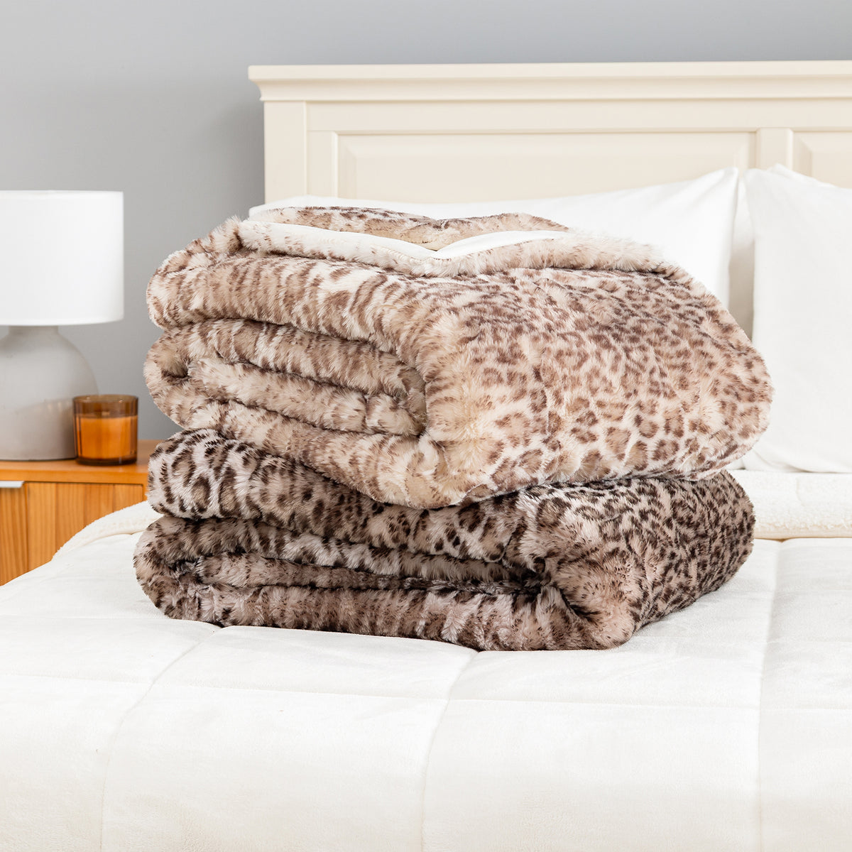 Two folded Leopard Faux Fur Throws stacked on a bed, Pink Leopard on top and Natural Leopard below.