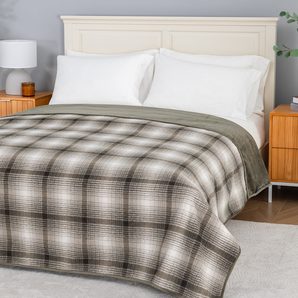 A plaid teddy fleece blanket dressed neatly on a bed in a bright bedroom.
