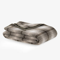 A plaid teddy fleece blanket folded neatly on a white surface.