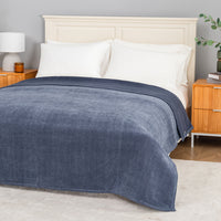 Dusty blue chenille knit blanket dressed neatly on a bed in a bright bedroom.