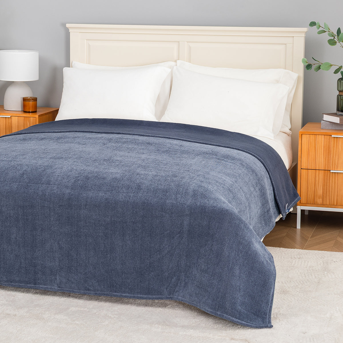 Dusty blue chenille knit blanket dressed neatly on a bed in a bright bedroom.