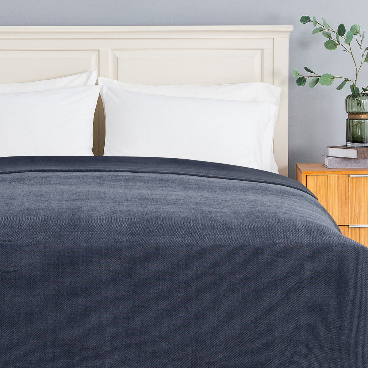 Dusty blue chenille knit blanket dressed neatly on a bed in a bright bedroom.