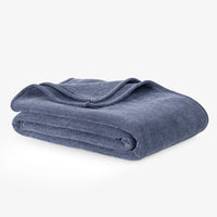 Dusty blue chenille knit blanket folded neatly on a white surface.