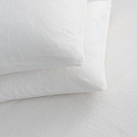 Two white textured pillows stacked on a white bedsheet surface.