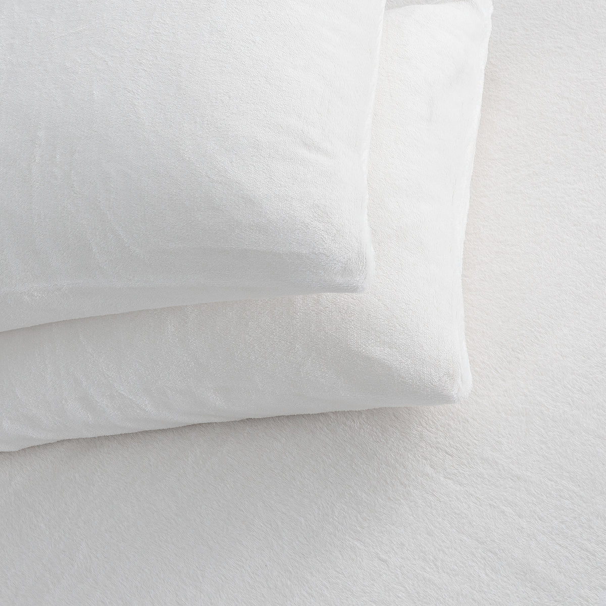 Two white textured pillows stacked on a white bedsheet surface.