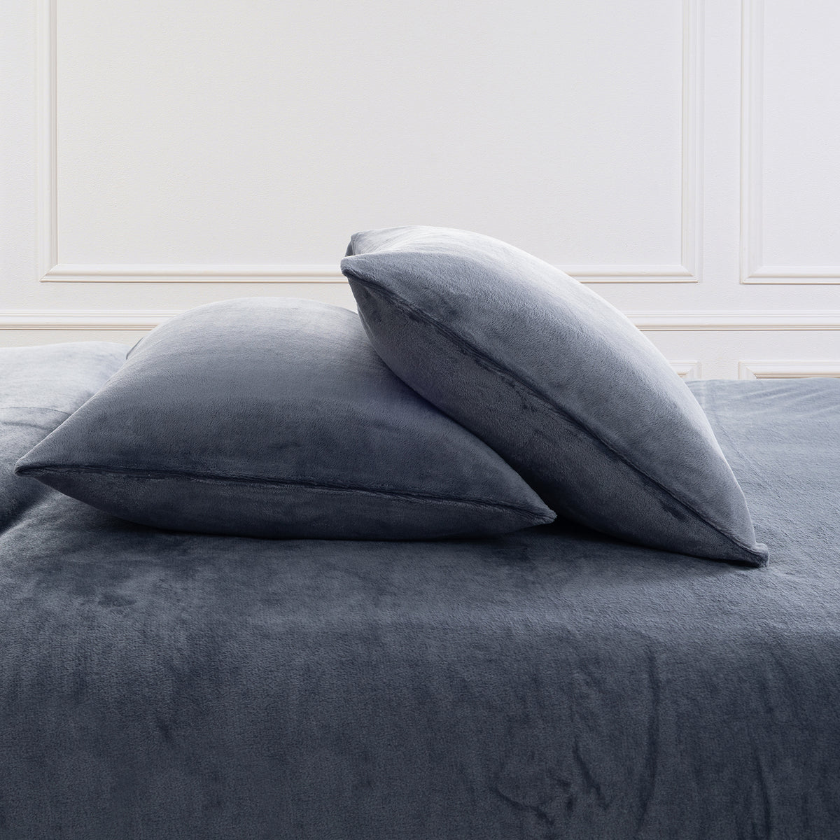 VelvetLoft® Plush Sheet Set pillowcases in Galaxy Blue on a made bed against a white paneled wall