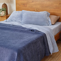 VelvetLoft® Plush Sheet Set in Polar Blue on a bed with a wooden headboard, partly covered by a navy blanket