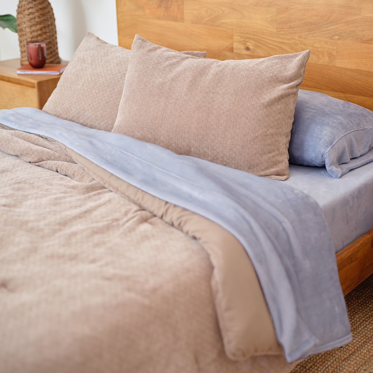 VelvetLoft® Plush Sheet Set in Polar Blue under a tan comforter and pillows on a bed with a wooden headboard