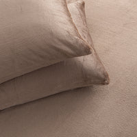 Two plush, textured beige pillows resting on a matching beige bedspread or blanket.