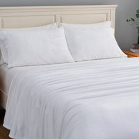 White textured bedding set including a duvet cover and two pillows, neatly arranged on a bed with a light wood headboard.