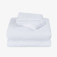 A stack of folded white towels, with a smaller folded towel placed on top of a larger one, photographed on a plain light gray background.