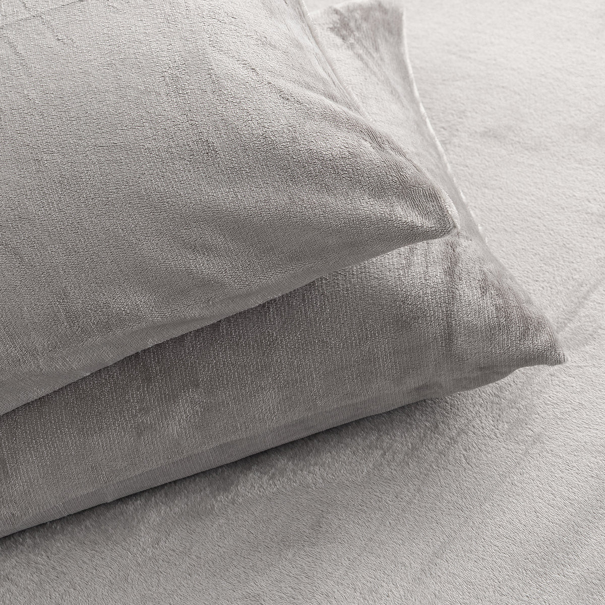 Two light gray textured pillows resting on a matching light gray bedspread or blanket.