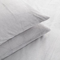 Two light gray plush pillows resting on a matching gray textured bedsheet.