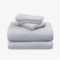 A stack of three folded light gray bedding pieces, likely a sheet set, on a plain white background.