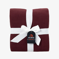 A Polartec Microfleece Blanket in deep fig folded neatly on a white surface.