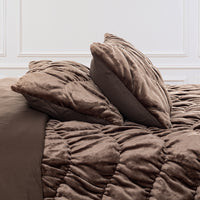 A brown ruched VelvetLoft Comforter Set decorated on a bed in a bright room.