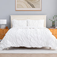 A white ruched VelvetLoft Comforter Set decorated on a bed in a bright room.