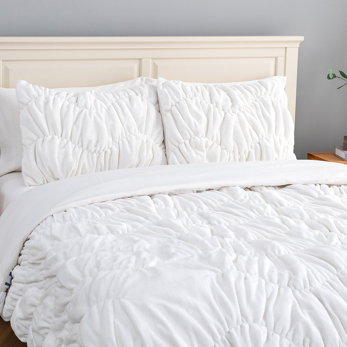 A white ruched VelvetLoft Comforter Set decorated on a bed in a bright room.
