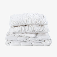 A white ruched VelvetLoft Comforter Set folded neatly on a white surface.