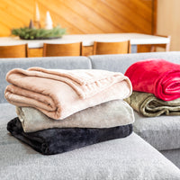 Stack of folded blankets in various colors on a gray sofa.