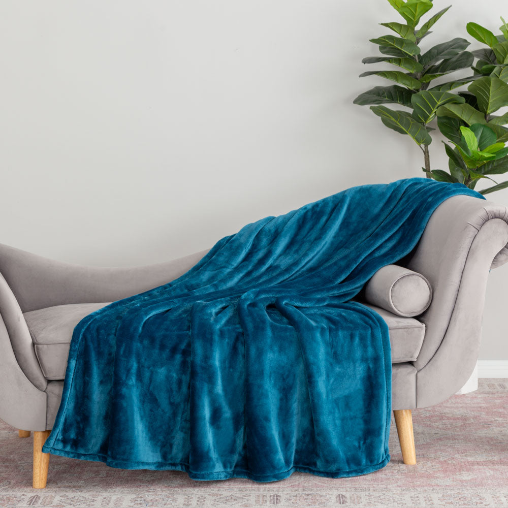 Blue blanket draped over a gray sofa with a plant in the background
