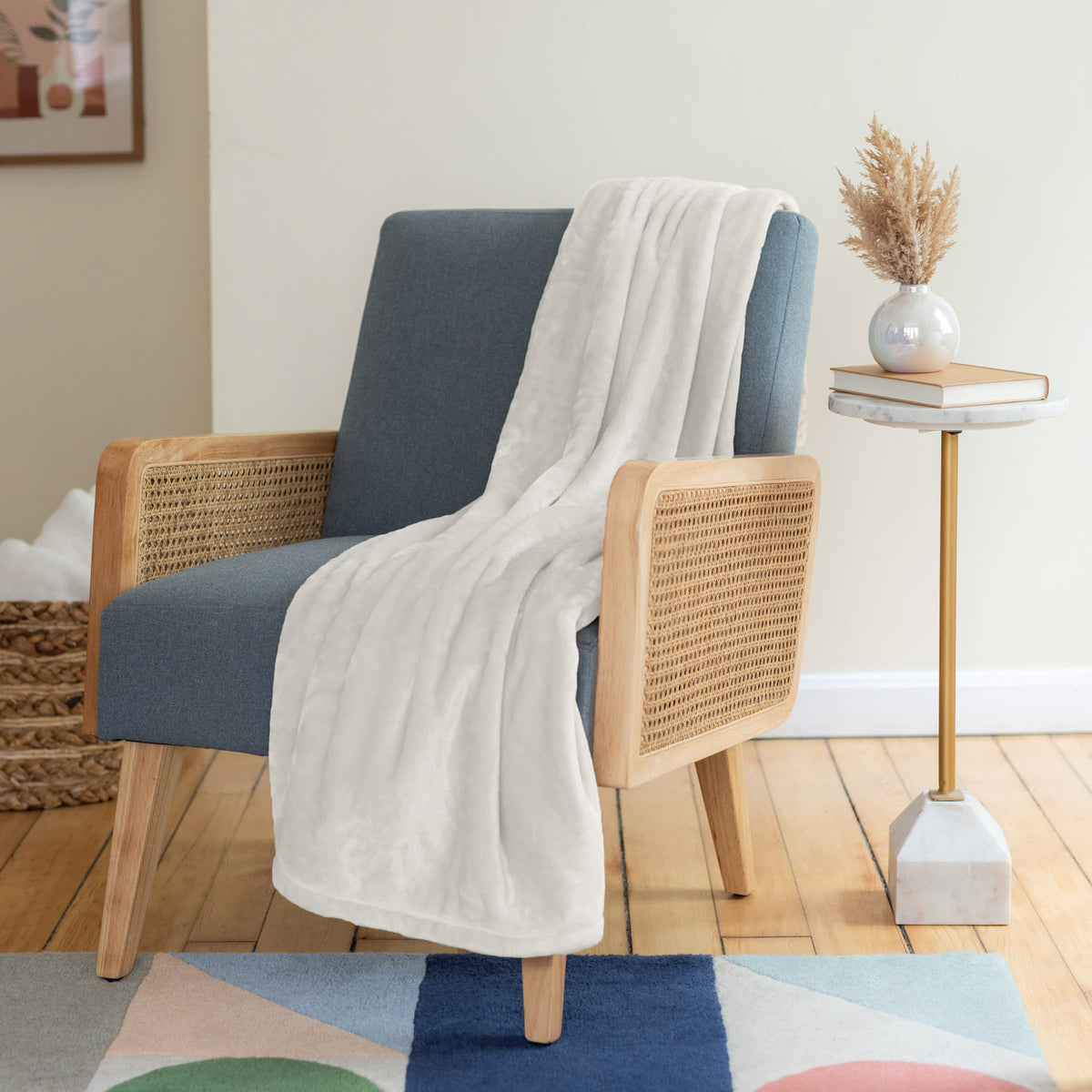 White blanket draped over a blue armchair in a room with a side table and decorative elements.