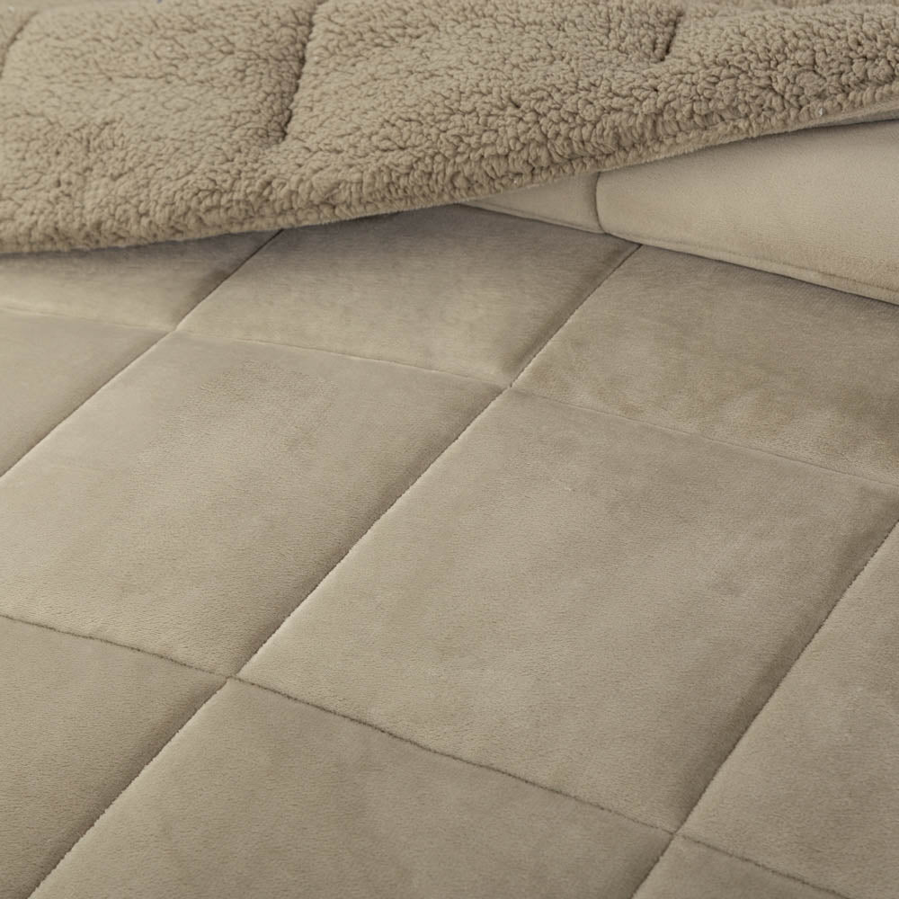 A close-up of a green quilted comforter showing its soft texture and stitching.