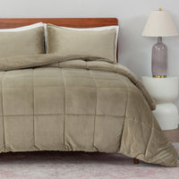 Beige comforter set on a bed with pillows and a lamp in the background