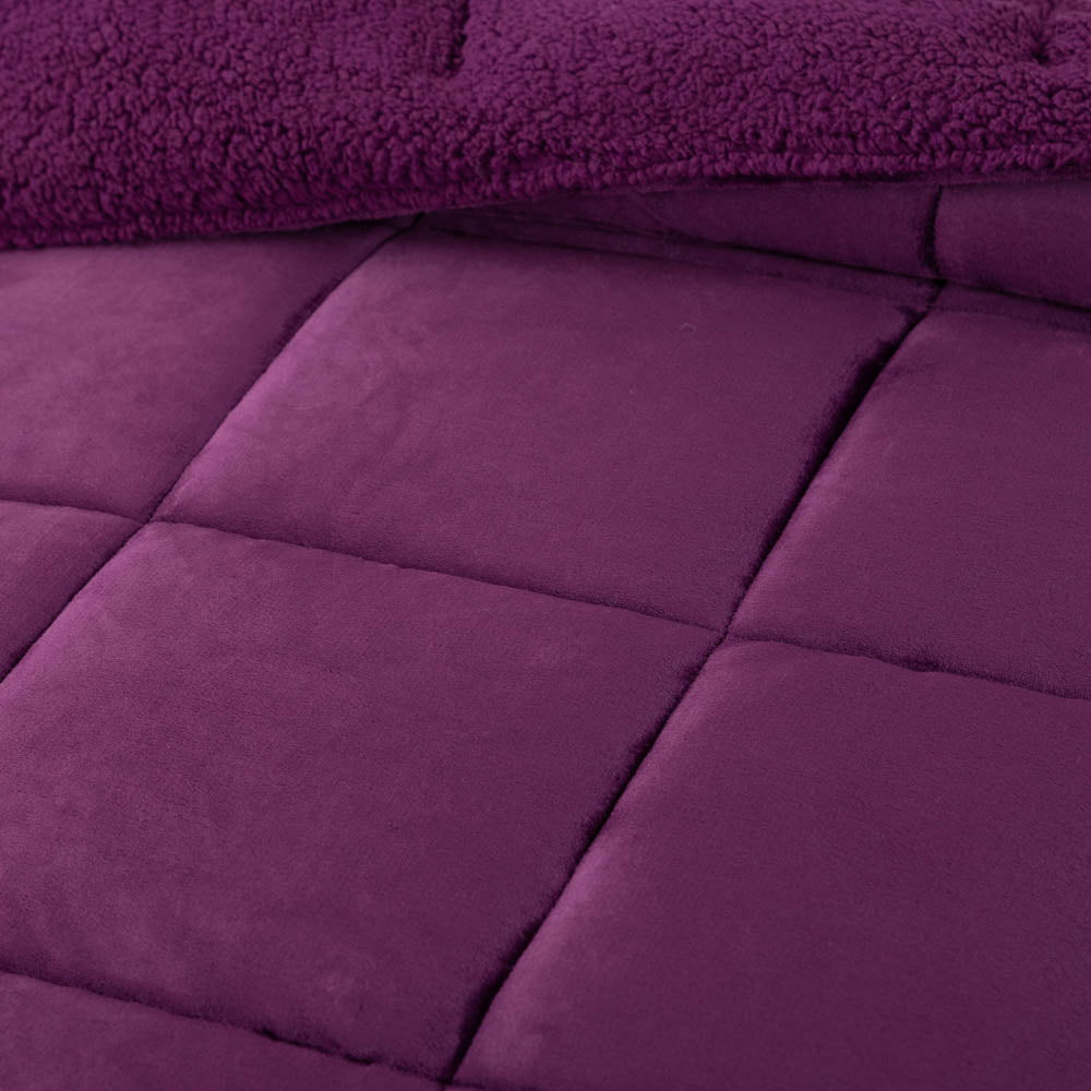A close-up of a purple quilted comforter showcasing its stitching and soft texture.