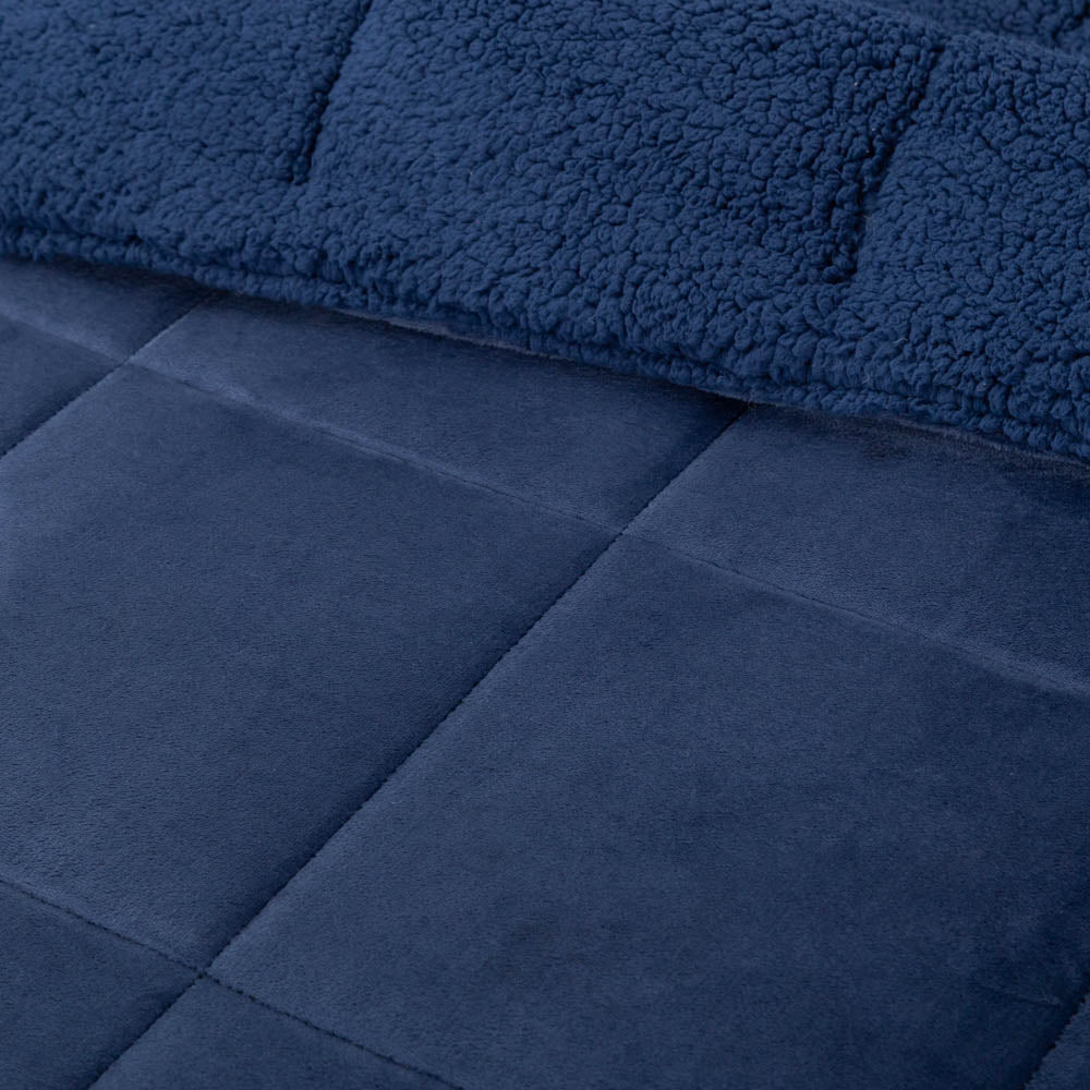 A close-up of a navy quilted comforter showing its stitching details.