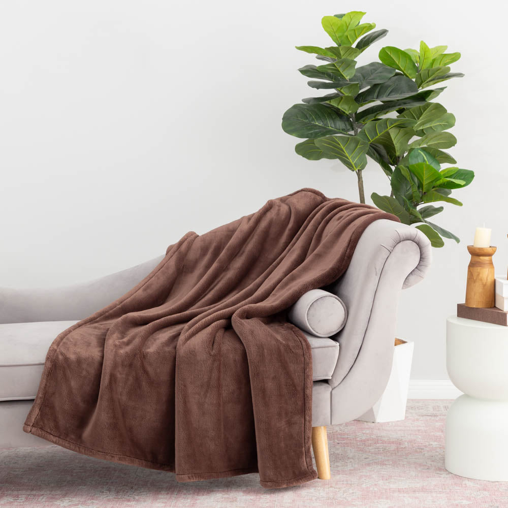 A brown PrimaLush Throw draped neatly over a grey chair.