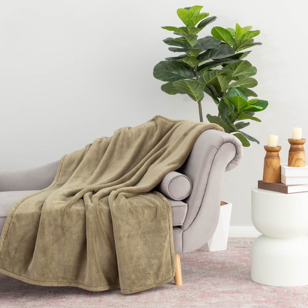 A green PrimaLush Throw draped neatly over a grey chair.