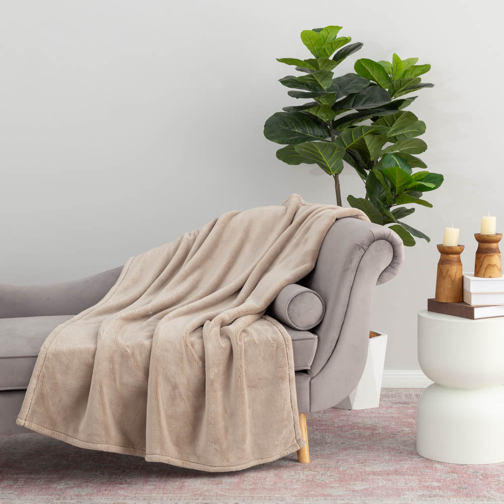 A beige PrimaLush Throw draped neatly over a grey chair.