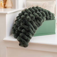 Dark green textured blanket draped over a white surface with a light background