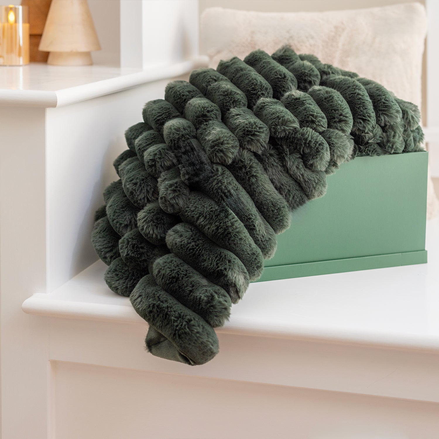 Dark green textured blanket draped over a white surface with a light background