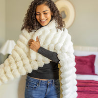 Woman wrapped in a white fluffy blanket indoors