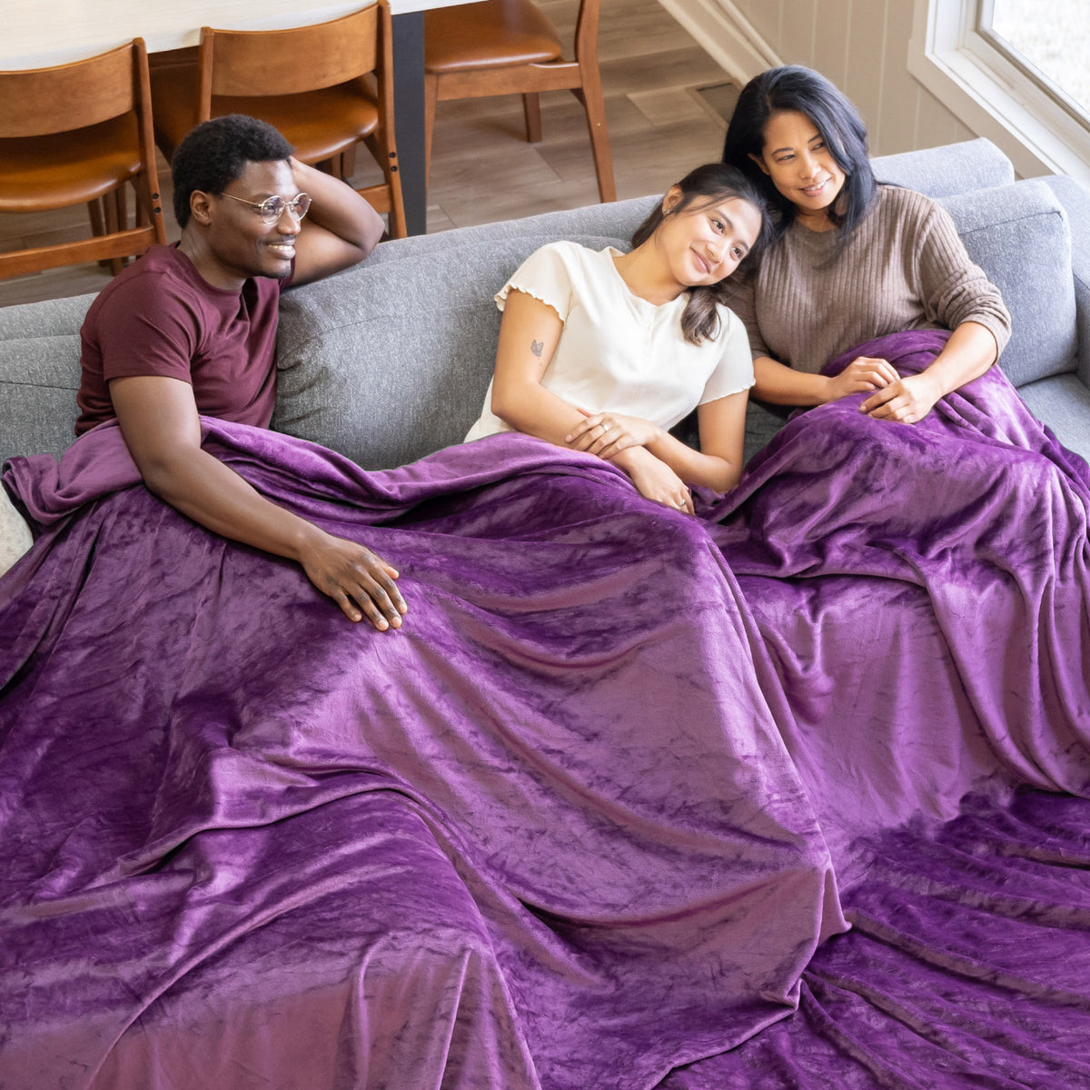 Image of a family sharing a purple VelvetLoft® blanket on the couch. 
