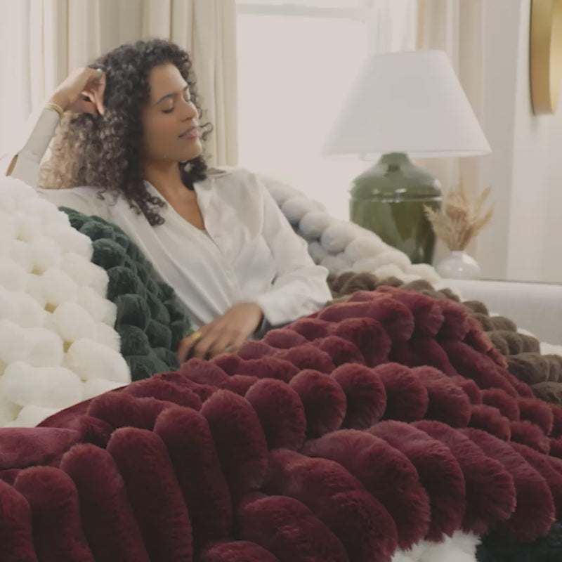 Faux fur throw video with a model laying underneath colorful faux fur throws.