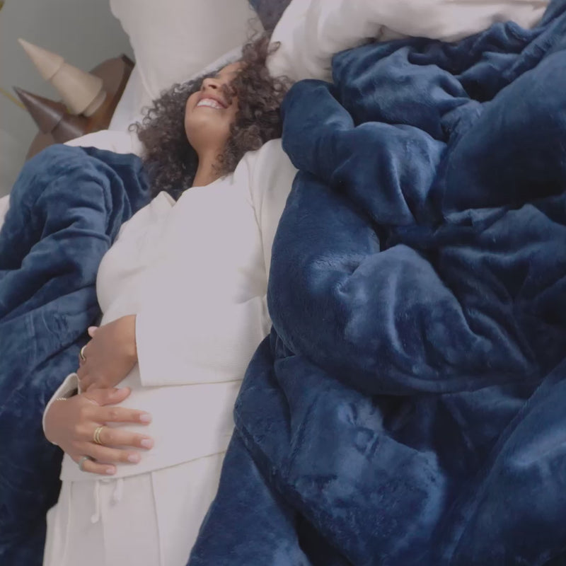 A video of a model laying on a VelvetLoft Duvet Set in Blue while laughing.