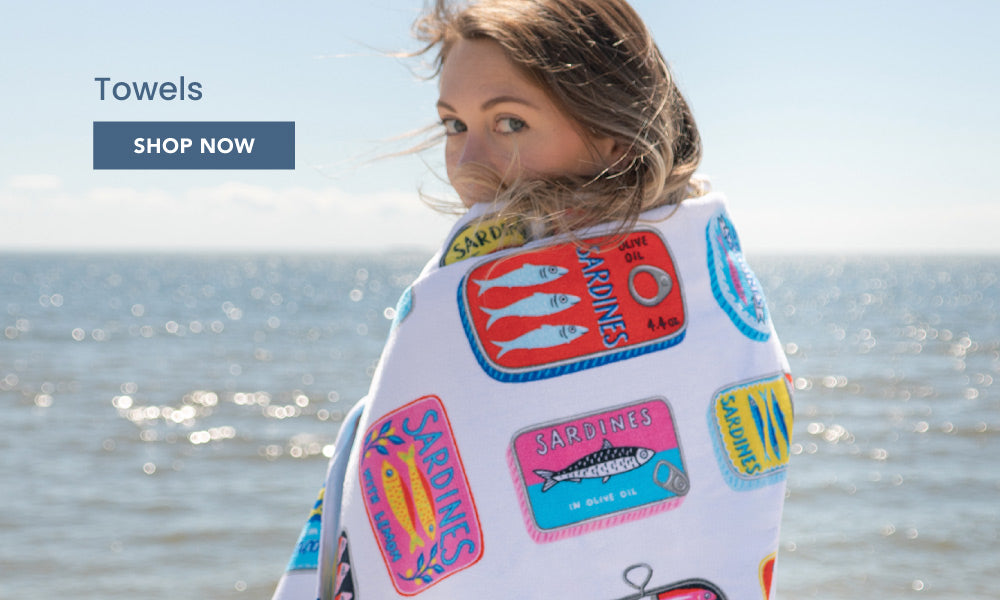 An image of a woman wrapped in a towel at the beach. There is text that reads, "Towels. Shop now."
